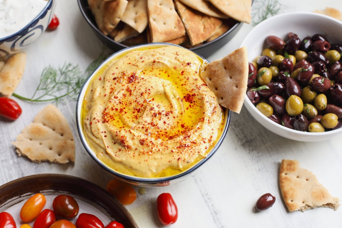 Overhead view of Greek meze platter with hummus, pita bread, olives, and tzatziki