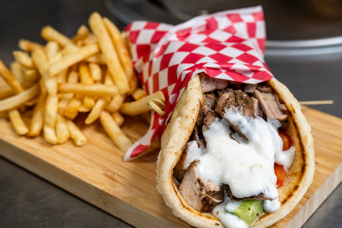 Chicken gyros in pita bread with tzatziki, tomato, onion and fries