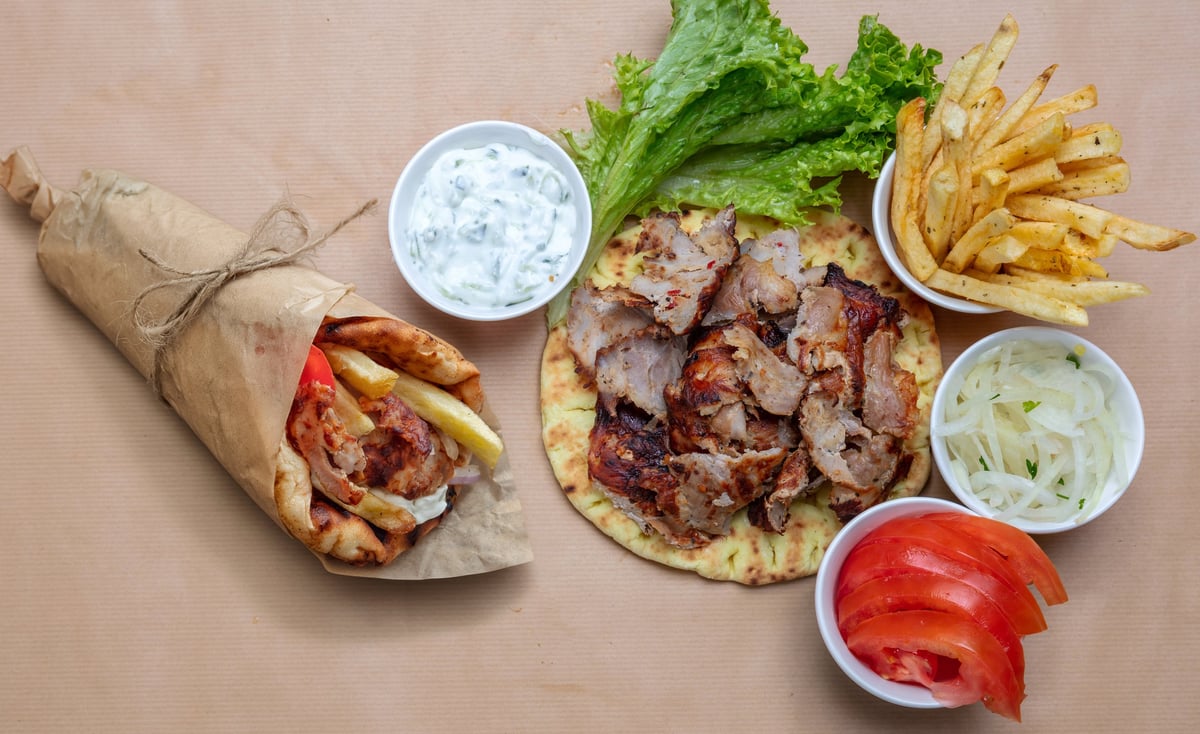 Greek gyros platter and wrap served with fries, tzatziki, lettuce, onions, and tomatoes